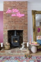 Neon sign on a brick chimney breast with a wood burning stove