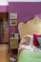 Gold painted French bed and side table in a pink bedroom