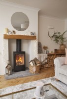 Living room showing a fire lit in a wood burner stove and log storage.
