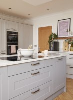 Kitchen detail showing integrated hob, grey cabinets and oven.