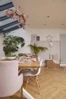 Contemporary dining area in open plan space with wooden flooring, pink panelling and velux windows.