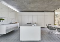 Contemporary kitchen diner with white furniture and concrete floor