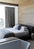 Bed and bath in contemporary bedroom with wooden walls