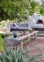 Rustic outdoor dining and kitchen area with pizza oven