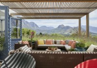 Wooden pergola above outdoor seating area with views of mountains