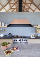 Large extractor hood above range cooker in contemporary kitchen