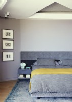 Grey and yellow bedding on bed in modern bedroom