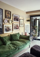 Display of family photographs and artwork above green sofa
