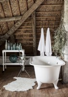 White rolltop freestanding bath in rustic attic bathroom