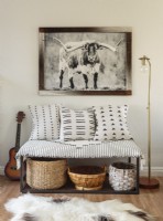 Appreciation for Western culture is on display and includes a favorite print framed using reclaimed wood. Baskets, lamp, and bench textiles contribute to the cozy spot's appeal.