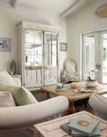 Outfitted with comfortable sofas and chairs, the family room doubles as a reading room. A vintage armoire conceals the T.V in style. The French doors open onto a loggia, the pool and the view of the bay.