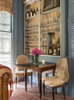 In a corner of the living room, Renee creates the feel of an elegant Parisian cafe with a wine glass-lined wall, stylish table and dressed up chairs.