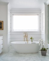 Gold fittings add a touch of luxury to the soaking tub. The pure white and simplicity of the setting confers a spa-like mood of the master bathroom.  