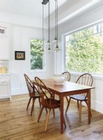 The kitchen eating area shines with the simplicity of the antique Windsor chairs and Shaker table.  The quartet of light pendants has a vintage feel with a modern twist.
