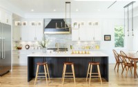 Uniting modern white cabinetry with the graphic black hood and island gives the kitchen a sophisticated contemporary farmhouse style. The brass chandelier, which came with the house, is in sync with the sleek design. 