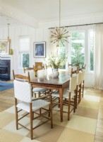 The antique dining room table that once belonged in a French bakery and the Shaker-style white woven chairs, assembled by Neal from a kit many years ago, have followed the couple from house to house.  â€œLuckily, many of the pieces we bought years ago have withstood the test of time,â€ Linda notes. The Sputnik-style chandelier casts a retro-modern glow.