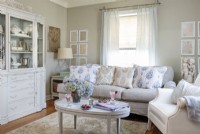 Cohesive tones and textures and plenty of light give a spacious feel to the small living room. The down-filled linen slipcover sofa was a $25 estate sale score. Fabric stretched over a canvas and framed French documents from the 1700s add subtle pattern to walls. End tables work double duty by offering hidden storage.