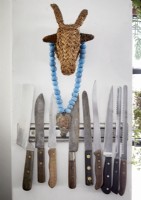 Detail of knives on wall magnet strip with straw bull ornament