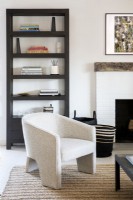 Modern white upholstered armchair and bookcase.