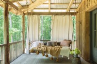 The 12-feet deep wrap-around porches is Annie's favorite feature of the cabin. Darryl constructed the swinging bed using barn wood while Annie made it cozy with throws and pillows.