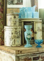 A robinâ€™s egg blue milk glass pitcher set mingles with vintage metal sugar, bread, and flour tins. 