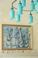 A teal blue glass chandelier adds an unexpected dash of color up high. A bunny painting inspired the roomâ€™s palette.