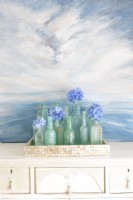 A painting by Erin forms the perfect backdrop for collection of vintage aqua bottles. 