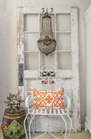 An Egyptian crystal chandelier unites with a vintage door and garden chair.
