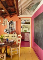 Raspberry shades brighten both the dining room wall and kitchen floor for design continuity. 