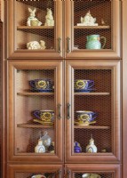 Treasures displayed in a wire-front cabinet include vintage sunflower cups and saucers, mustard jars,