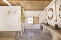 Concrete finishes and reed ceiling in farmhouse bathroom