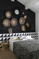 Display of baskets on black wall of monochrome bedroom