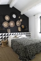 Display of baskets on black wall of modern monochrome bedroom
