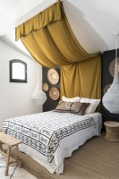 Modern country bedroom with draped material above bed