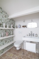 Sink and toilet in bathroom with floral wallpapered feature wall
