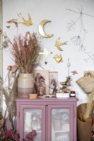 Pink painted cabinet covered in ornaments and flowers