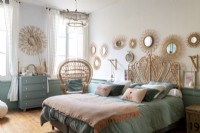 Bedroom with wicker headboard and display of mirrors on wall