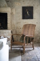 Wicker armchair in country living room with exposed stone walls