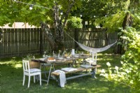 Large picnic table in shade with hammock in country garden