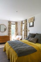 Yellow and grey bedding in modern bedroom with patterned curtains