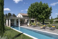 Swimming pool and loungers on decked area outside country home