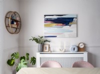 Artwork above radiator cover shelf in modern feminine dining room