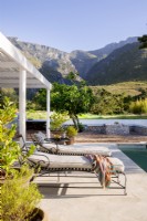 Metal loungers beside pool with mountain view