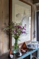 Vase of wild flowers on shelf with modern sailing painting behind