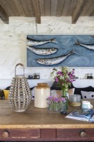 Large and comfortable rustic kitchen with wooden farmhouse table and large modern artwork of fish in a blue sea.