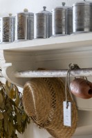 Kitchen shelving detail, with straw, hat, and metal storage containers