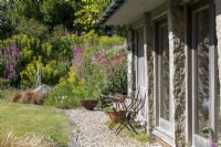 Sally and John Biddle's house in Cornwall, the exterior showing a lovely summer garden with stone barns and house
