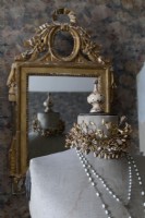 Detail of dressmakers mannequin wearing jewellery and gilded mirror
