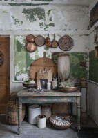 Copper pots and pans on distressed painted wall of rustic kitchen