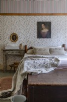 Country bedroom with antique portrait painting on floral wallpaper